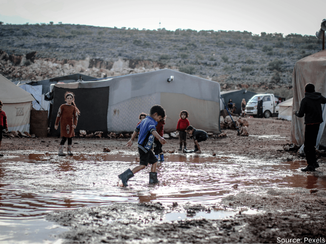 children playing in mud at a refugee camo